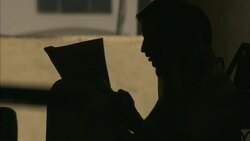 A man sits and reads a newspaper in silhouette. Stock Footage