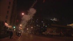 A man holds fireworks as they shoot into the air and explode. Stock Footage