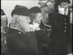 Uniformed members of the WAVES hold their fingers in their ears as guns blast on ships. News Clip