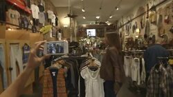 fashion blog filming girl walk through vintage clothing store Stock Footage