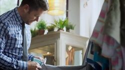 Shop owner prices and tags shirtsleeve with tagging gun in clothing store Stock Footage