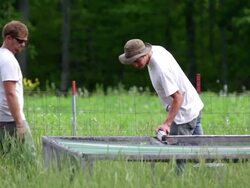 MS SLO MO PAN Shot of Two young farmers tends to chickens in chicken tractor / Chatham, Michigan, United States Stock Footage