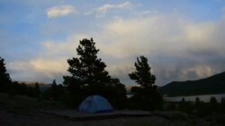 Camping Tent Stands alone as the Sun sets and clouds build Alpine glow comes out the colors of the evening set into the Colorado Background Stock Footage