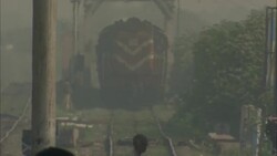 Pedestrians cross railway tracks in front of a slow-moving train in India. Stock Footage