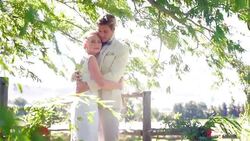 Bride and groom hugging under windy tree Stock Footage
