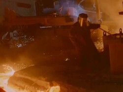 MS Shot of Man in protective gear stoking river of molten metal Stock Footage