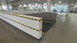 Fluorescent lights shine above a ramp and giant showroom in an automobile distribution center. Stock Footage