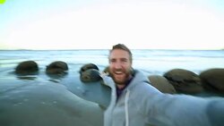 Cheerful man stands near the Moeraki boulders,takes selfie portrait Stock Footage