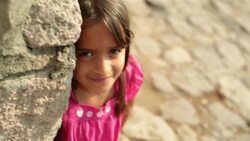 Cute young hispanic girl smiles at camera on third-world street corner Stock Footage