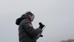 Young man looking at tablet on frozen pond in winter in rural Montana, USA. Stock Footage
