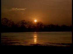 WA Orange sunlight reflecting on water at dusk, bright sun in sky, India Stock Footage
