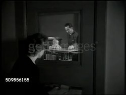 1946: TESTING BABY: DRAMATIZATION: Social Worker watching baby through door window being tested by doctor, making notes while sitting behind door. Instructional Video