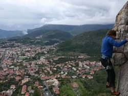 Father instructs son climbing rock cliff, sea below Stock Footage