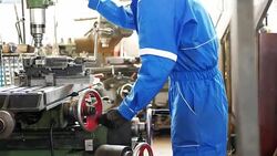 Worker in protective suit working in factory on machinery Stock Footage