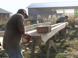MS Carpenter using power sander on support beam during framing of an energy efficient post / Grass Lake, Michigan, USA  Stock Footage