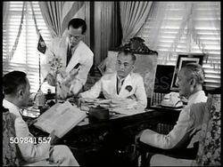 1940: MALACANANG PALACE: EXT WS Malacanang Palace, car. INT Philippine President Manuel L. Quezon (1878-1944) at desk w/ men. CU Quezon talking, holding cigarette. MS Quezon talking at desk. MS American & Philippine flags on poles. Instructional Video