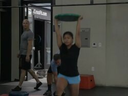Jonice performs series of overhead lunges; Steven performs dumbell snatches in background. Stock Footage