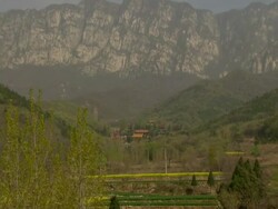 Wide Shot Long Shot Zoom In - Roofs and pagoda of a chinese temple in a valley with rugged mountains in background / China Stock Footage