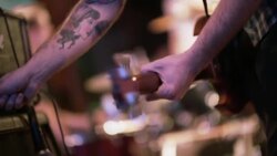 Guitarist plugs cable into amplifier and flips amp switch on stage before show Stock Footage