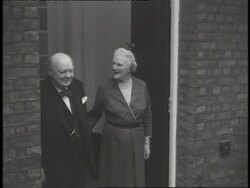 Prime Minister Winston Churchill gives the victory sign as his wife Clementine waves from a doorway. News Clip