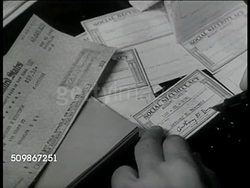 1947: FORGING SIGNATURES: DRAMATIZATION: INT MS Man sitting in dark room w/ checks. CU Signing Social Security card. MS Crook leaving w/ papers. USA Instructional Video