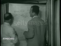 1938: COAST GUARD REPORT: DRAMATIZATION: Sailor bringing dispatch to two men sitting in Intelligence office, men looking AT 'Customs Enforcement' maps. Coast Guard sailors gather for meeting w/ Officer reading orders, investigate possible gun runner. Instructional Video