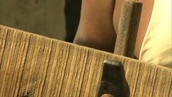 A man wearing eyeglasses helps another man repair the side of a boat. Stock Footage
