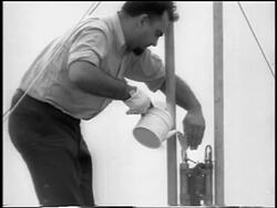 B/W 1933 man pouring fuel into world's first liquid-fueled rocket / newsreel Stock Footage