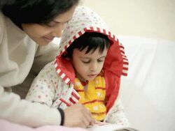 Little boy filling color in coloring book with his mother Stock Footage