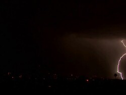 Several very bright bolts of lightning strike down amongst city buildings during night time Arizona Monsoon thunderstorm Stock Footage