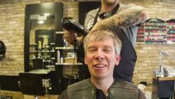 Male Hair stylist using a hair dryer on a male client Stock Footage
