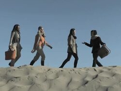 Friends walking along sand dune with picnic basket Stock Footage