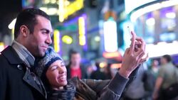 Young couple make funny faces taking photos together with smartphone in Times Square Stock Footage
