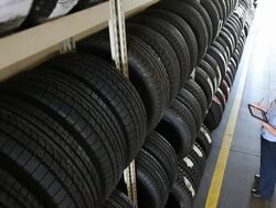 MS Mechanic walking up to large rack with tires and checks an entry on tablet computer, before turning and walking away / Seattle, Washington, United States  Stock Footage