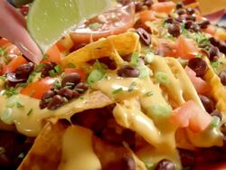 CU lime wedge squeezed over party platter of nachos Stock Footage