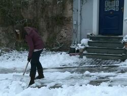 WS  Woman removing snow from street / Saarburg, Rhineland-Palatinate, Germany Stock Footage