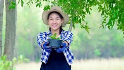Protect the nature - Teenager girl holding a potted plant in a garden Stock Footage