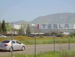MS Shot of TESLA factory of automobile manufacturing plant with traffic moving on freeway / Fremont, California, United States Stock Footage