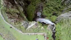 Man traverses highline stretched above waterfall, valley Stock Footage