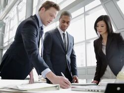 Business people reviewing blueprints at desk Stock Footage