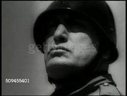 1935: ITALY-ETHIOPIAN WAR: EXT CU Italian Dictator Benito Mussolini standing. MS Officer Pietro Badoglio (1871-1956) looking through telescope from bunker. HA WS Soldiers charging across field. WS Variation of L 3-33 light tank crossing field. Army Instructional Video