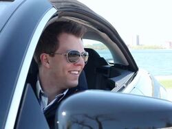 CU Young man sitting in his modern car and smiling on sunny day near lake / Minneapolis, Minnesota, United States Stock Footage