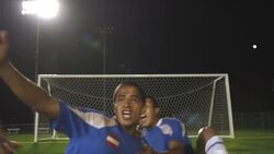 A soccer team celebrates their victory while the goalie of the opposing team crouches in disappointment. Stock Footage