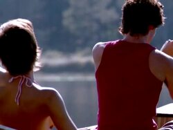 Slow motion tilt up couple rowing canoe on lake / woman's hand scooping water Stock Footage