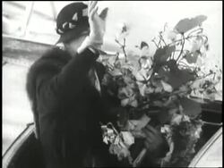 First Lady Eleanor Roosevelt holds flowers, waves and smiles at the doorway of an airplane. News Clip