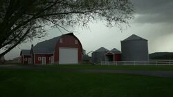 Red barn and grain silos on a dairy farm under heavy clouds Stock Footage