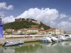 MS T/L Shot of Harbor with boats, lighthouse and castle / Castiglione della Pescaia, Tuscany, Italy Stock Footage
