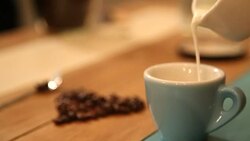 Pouring milk in coffee from barista Stock Footage