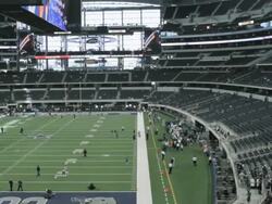  PAN Inside Cowboys Stadium before game time with empty seats and groups of people on the field and sidelines / Arlington, Texas, United States Stock Footage