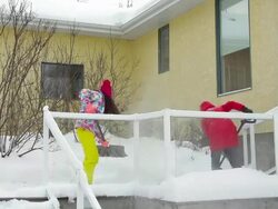 Mother and daughter shoveling snow off house deck and steps Stock Footage